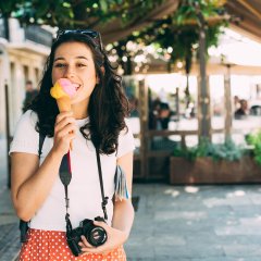 Happy young beautiful tourist woman enjoying a big ice cream