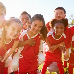 Kids in elementary school sports team piggybacking outdoors Kids in elementary school sports team piggybacking outdoors