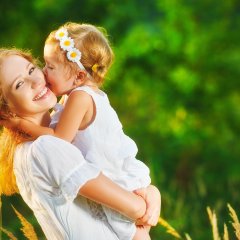 Happy family on summer. little girl child baby daughter hugging and kissing mother